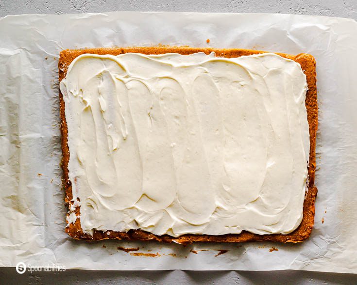 Sweet cream cheese filling spread out on top of the pumpkin cake. Ready to be roll-up. Recipe at Spoonabilities.com