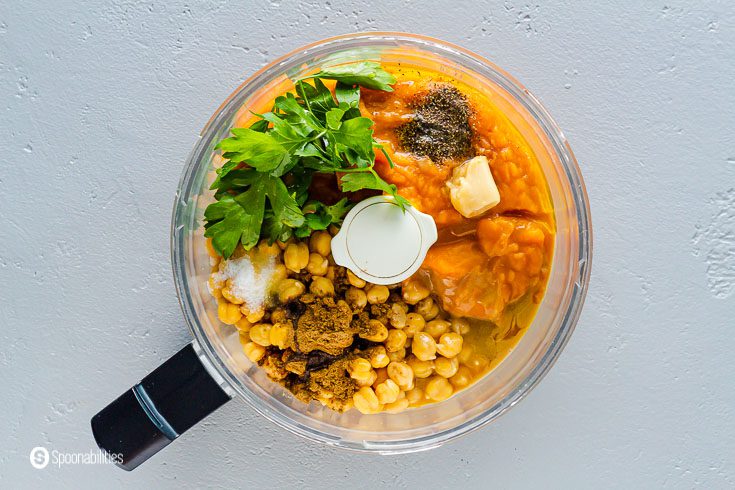 Ingredients in the food processor bowl for the hummus: chickpeas, parsley roasted garlic, lemon juice, cumin, pumpkin puree, and sea salt. Recipe at Spoonabilities.com