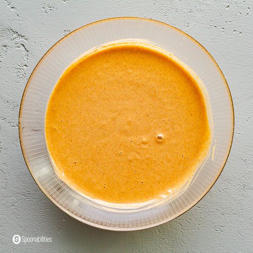 Pumpkin cake batter in a round glass mixing bowl. Recipe at Spoonabilities.com