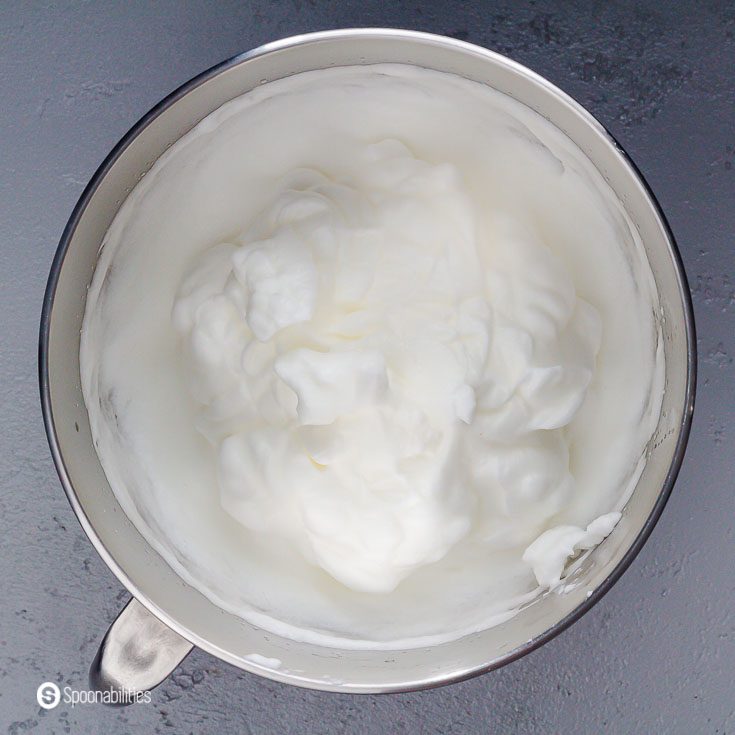 A metal mixing bowl with stiff peaks egg whites. Recipe at Spoonabilities.com
