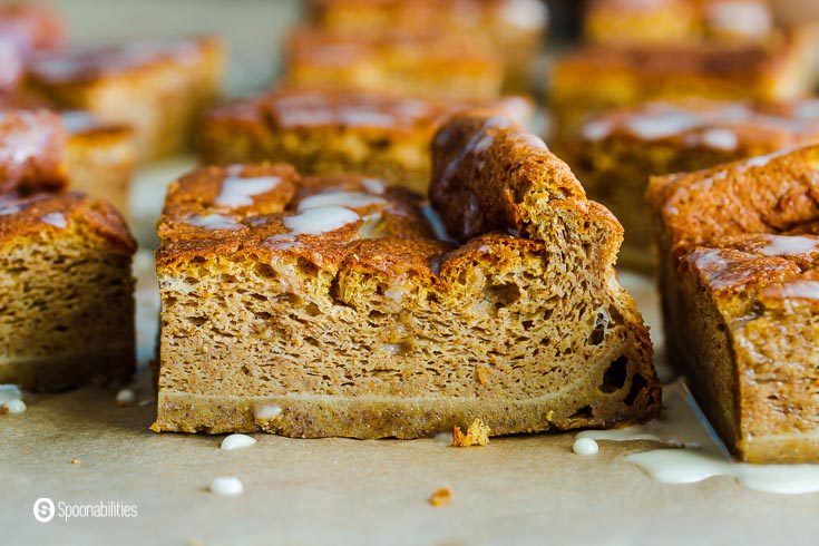 Close up photo of this custardy magic cake made out of Fall ingredients like pumpkin purée and pumpkin pie spices. The photos have one main piece of the pumpkin magic cake and other pieces in the background. Recipe at Spoonabilities.com