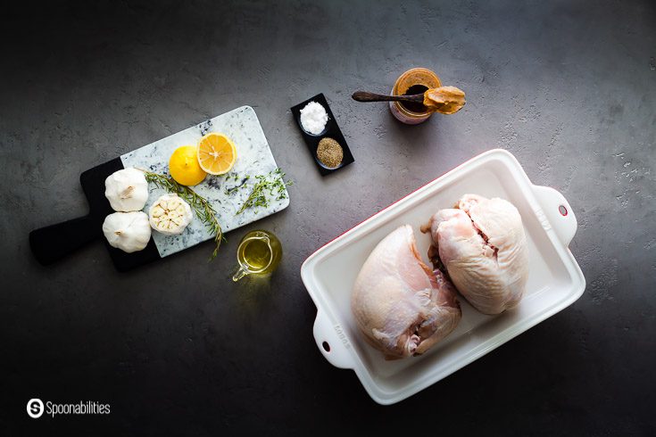 Photo with the ingredients for to roast the turkey breast: bone-in skin on turkey breast, brown butter, thyme, rosemary, wine, salt & pepper, head of garlic, and lemon. Recipe at Spoonabilities.com