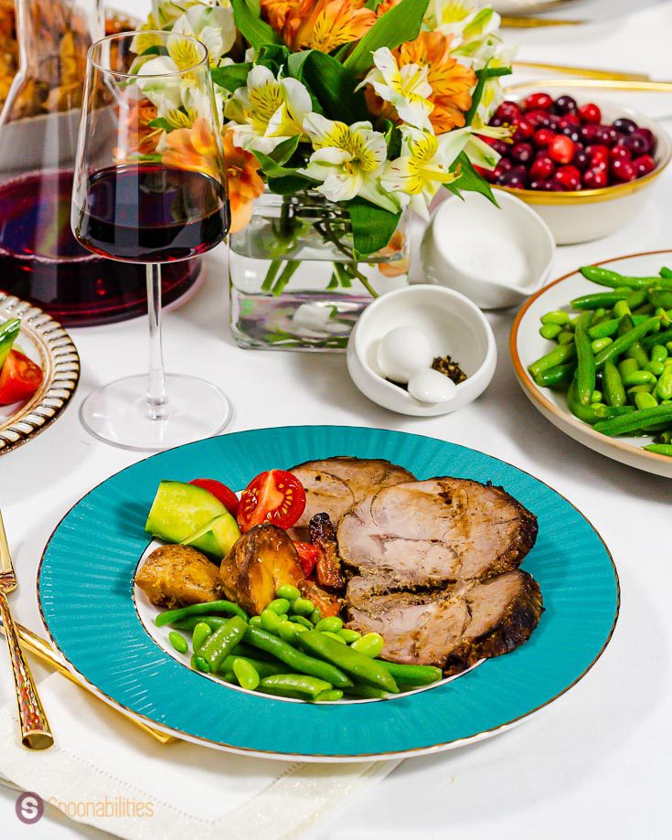 plate with a sea green edges plated with roast leg of lamb, cucumber & tomato salad, roasted veggies, and green beans. Recipe at Spoonabilities.com