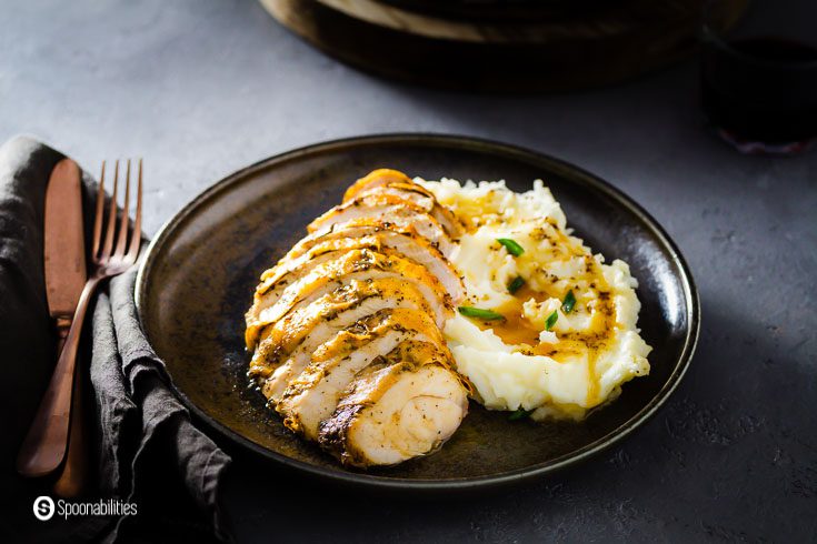 Slices of turkey breast with mashed potatoes on a plate. flatware and napkins on the left side of the photo. Recipe at Spoonabilities.com