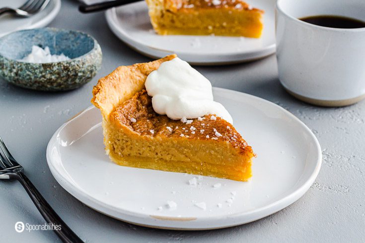 a small round plate with a piece of maple pie topped with whipped cream and sprinkles of flaky sea salt. Recipe at Spoonabilities.com