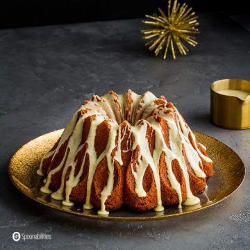 A Brandy Eggnog Bundt Cake on a large round plate with golden rim. Recipe at Spoonabilities.com