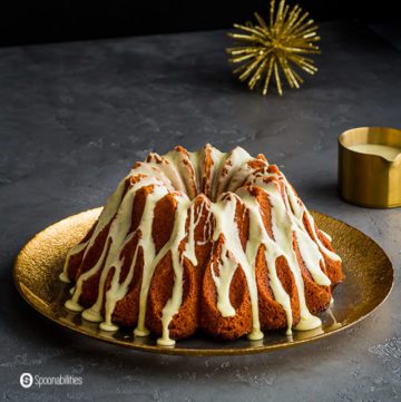A Brandy Eggnog Bundt Cake on a large round plate with golden rim. Recipe at Spoonabilities.com