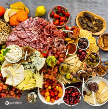 Overhead photo of a grazing table with a charcuterie board, cheeseboard, and gourmet products. Read more Charcuterie Board Ideas at Spoonabilities.com