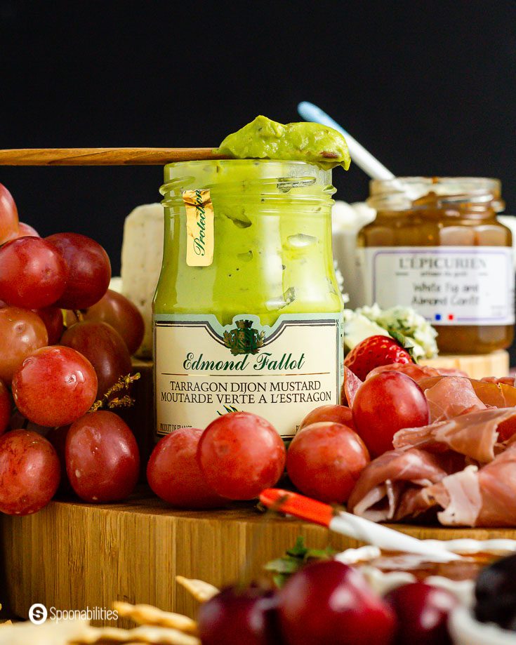 Close up of grapes around a jar of Edmond Fallot’s Tarragon Dijon Mustard - available at Spoonabilities.com