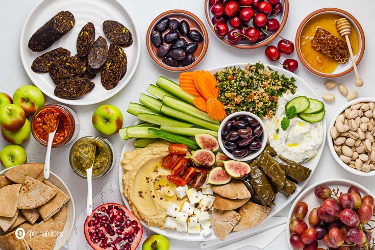 A large spread of delicious mezze dishes along with fruits and vegetables. Recipe at Spoonabilities.com