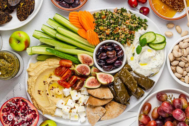 Close up of an oval white plate with mezze platter Greek appetizers. Check the recipe at Spoonabilities.com