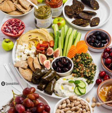An oval white plate with different Greek appetizers, vegetables, fruits, and spreads. Recipe at Spoonabilities.com