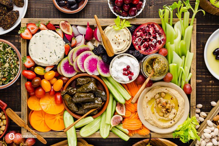 A close up photo from overhead to the Mediterranean Vegan mezze platter. The platter has fruits, vegetables, dips, vegan dips and spreads, and more. Recipe at Spoonabilities.com