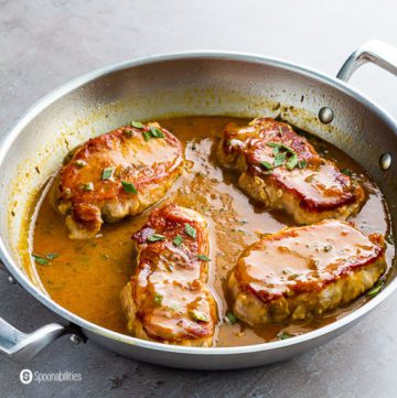 Sauté pan with four pork chops with apricot Dijon mustard sauce. Recipe at Spoonabilities.com