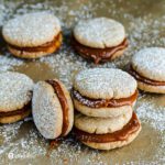 six Shortbread cookies on top of a parchment paper. The cookies are filled with Goat's milk caramel sauce aka Cajeta. Recipe at Spoonabilities.com