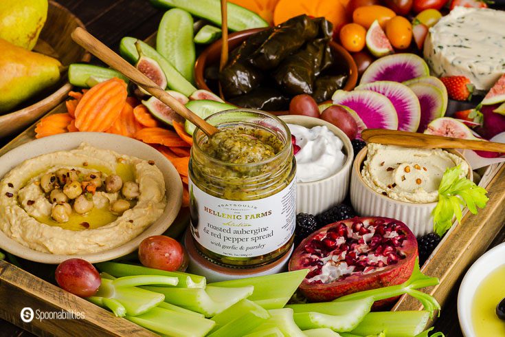 A jar of roasted eggplant dip in the center of the vegan appetizer board. The tray has dips, vegetables, fruits and vegan cheese. Recipe at Spoonabilities.com