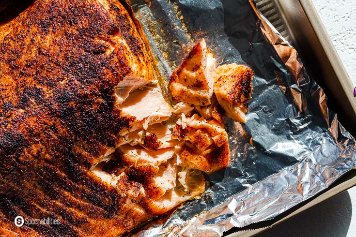 A photo of a salmon in a baking tray after came out of the air fryer. The salmon was seasoned with sat salt and chipotle pepper powder. Recipe at Spoonabilities.com