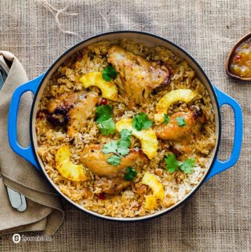 A blue cast iron casserole with the classic recipe chicken and rice casserole with Roasted pineapple habanero sauce. Recipe at Spoonabilities.com