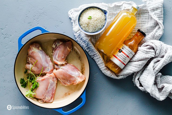 This photo has the ingredients for the chicken rice casserole. The ingredients are chicken thighs, white rice, chicken stock, roasted pineapple habanero sauce, and salt. Recipe at Spoonabilities.com