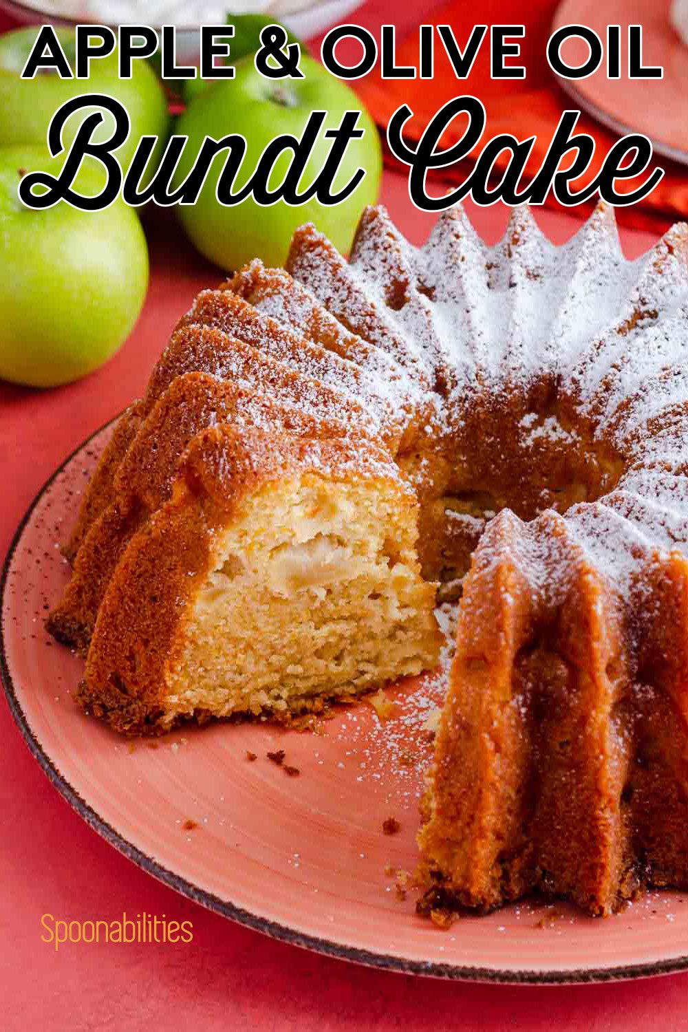 The apple and olive oil bundt cake is on a large plate, one piece of the cake is out, and it's showing the inside of the cake. The cake is dusted in powdered sugar. Recipe at Spoonabilities.com