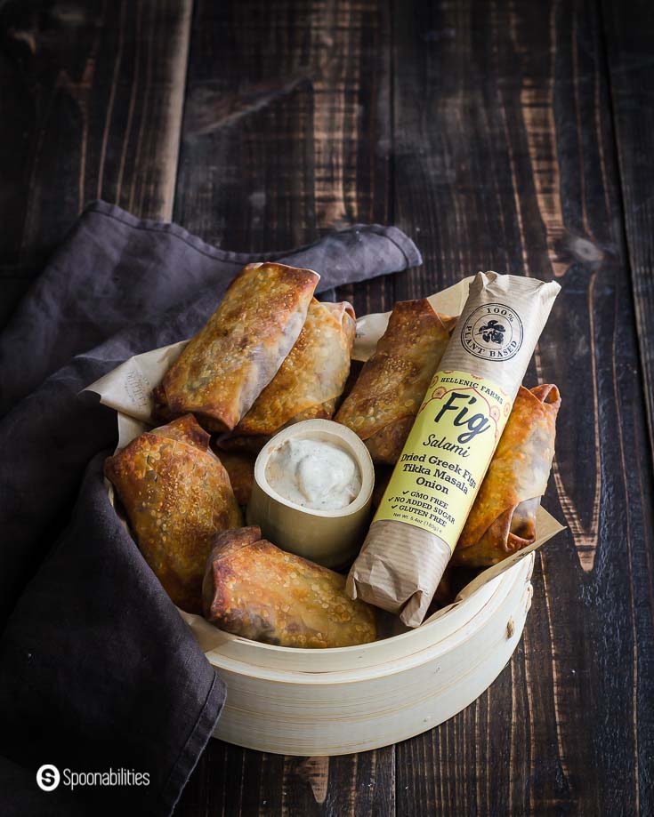 A basket with some air fryer egg rolls which are vegan made with vegan fig salami. Baked in the air fryer. Recipe at Spoonabilities.com