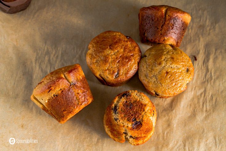 Five muffins on top of a brown parchment paper. The muffins are without the wrappers. Recipe at Spoonabilities.com