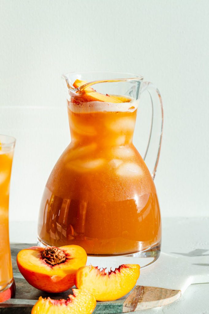 close up of large pitcher of peach iced tea