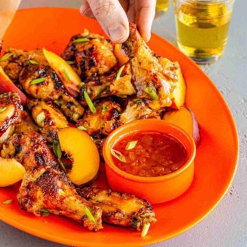 close up of chicken wing dipped in hot pepper peach bourbon sauce