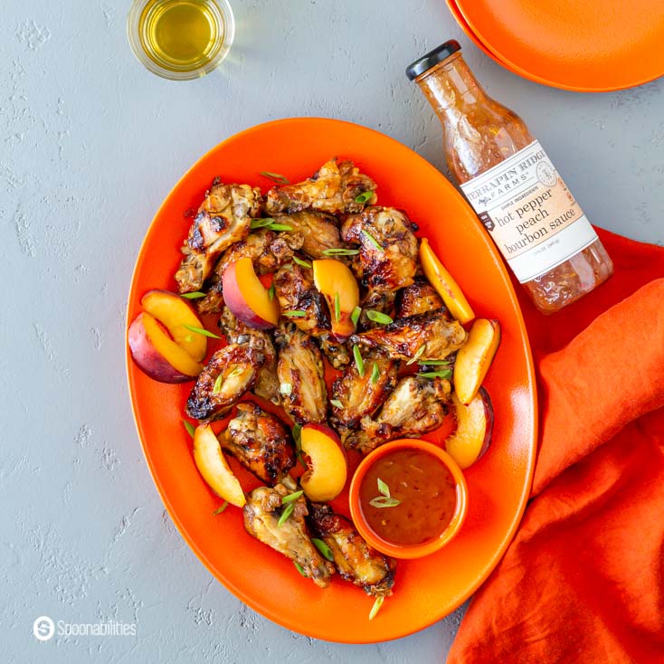 Hot Pepper Peach Bourbon Sauce next to plate of air fryer chicken wings