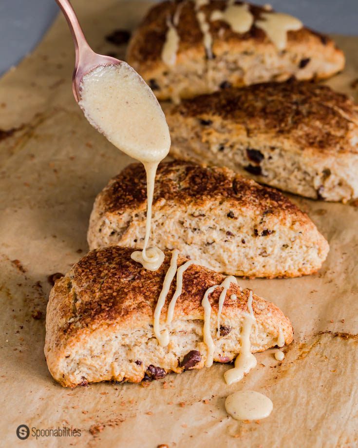 A hand drizzling brown butter maple glaze on the sourdough scones. Recipe at Spoonabilities.com