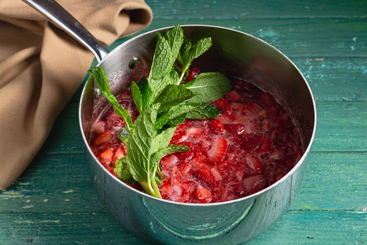 saucepan with strawberry puree and fresh mint sprigs