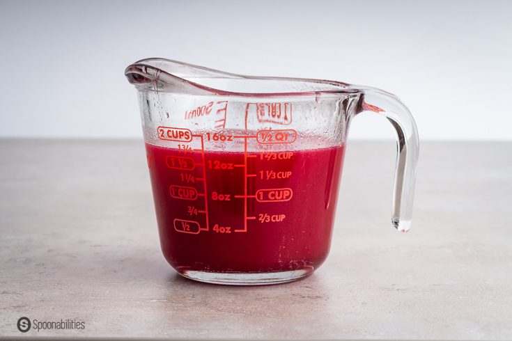 Prickly pear syrup in a measuring cup. Recipe at spoonabilities.com