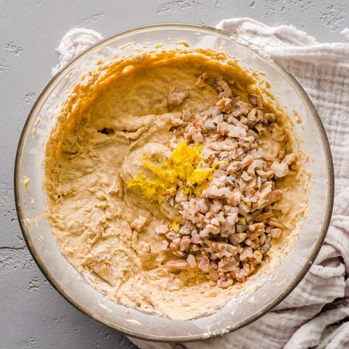 Adding the chopped walnuts and lemon zest to the bowl.