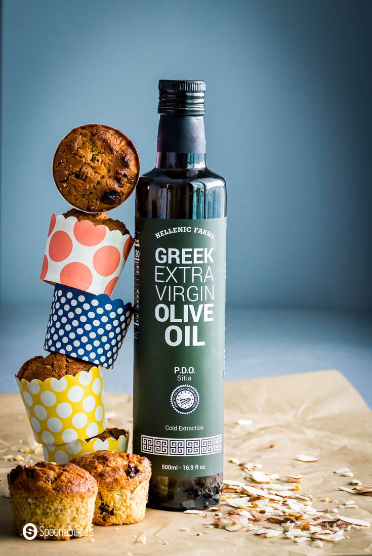 A bottle of Hellenic Farms Extra Virgin Olive oil. Next to the bottle several sourdough muffins forming a tower. Recipe at Spoonabilities.com