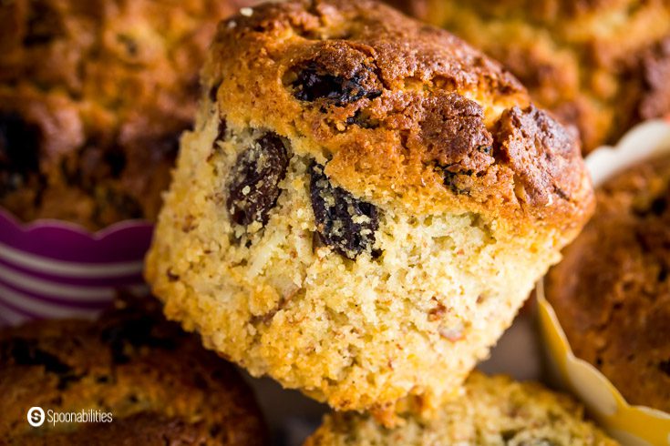 The photo has one almond sourdough muffins, it shows the inside with raisins and pieces of almond slices. Recipe at Spoonabilities.com