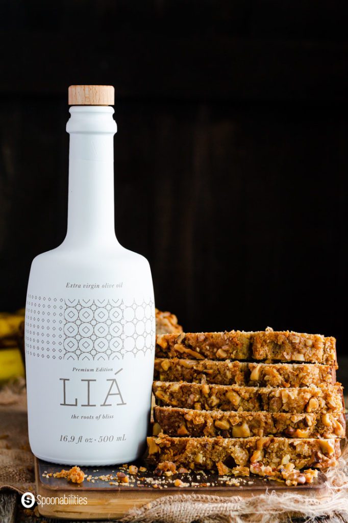 A Bottle of Lia Extra Virgin Olive oil next to a tower of slices of banana bread made with sourdough discard. Recipe at Spoonabilities.com