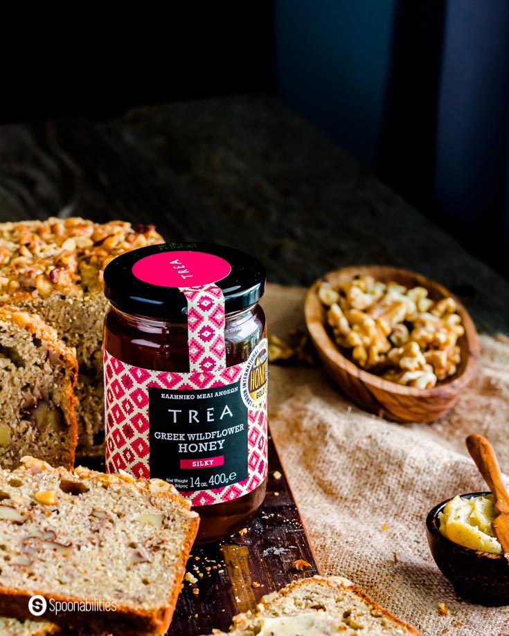 A jar of TREA Greek Wildflower Honey next to a tower of slices of banana bread made with sourdough starter. Recipe at Spoonabilities.com