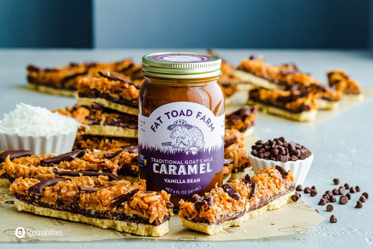 24 Samoas Cookie bars surrounding a jar of Fat Toad Farm Vanilla Bean Caramel Sauce