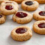 Six Thumbprint cookies filled in the center with jam.