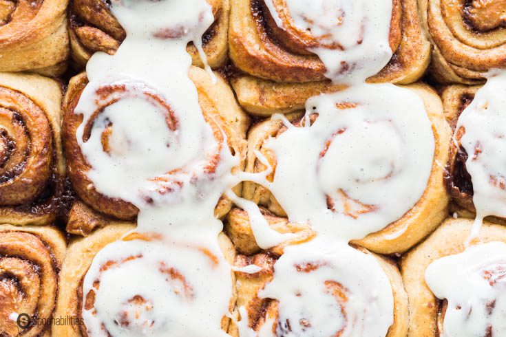 A close up photo with the Sourdough Cinnamon Rolls in the baking dish with cream cheese on top.