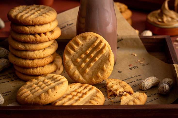 Close up of a peanut butter cookie standing next to a bottler with hot chocolate.