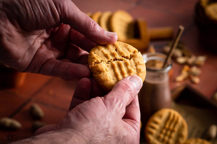 Two hands breaking a cookie in a half.
