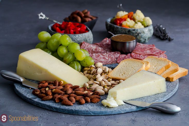 salami, cheese, nuts and grapes on a marble charcuterie board