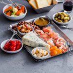 Metal tray with blue cheese, prosciutto, olives, toasts and other charcuterie items