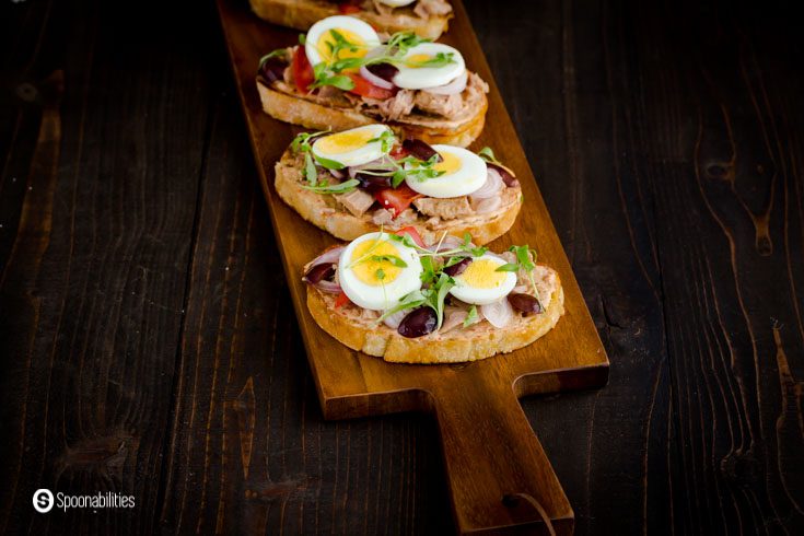 Three Toasts with canned tuna, kalamata olives, hard boil eggs, and garnished with herbs.