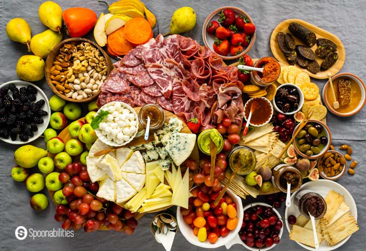 Overhead view of an impressive grazing table with a complete charcuterie board, cheeseboard, and gourmet products. Read more Charcuterie Board Ideas at Spoonabilities.com