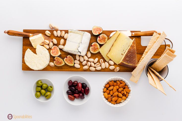 Charcuterie board with cream cheese, manchego, and blue cheese complemented by figs, nuts, olives.