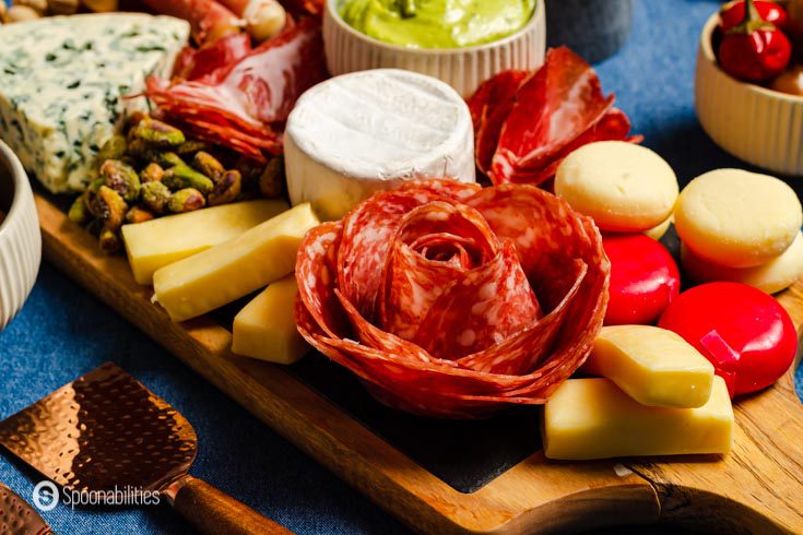 Arrangement of meats for charcuterie boards along with cheese, pistachios, and other snacks