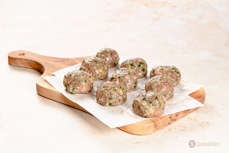 9 raw Swedish meatballs made of beef and pork sitting on a wood board