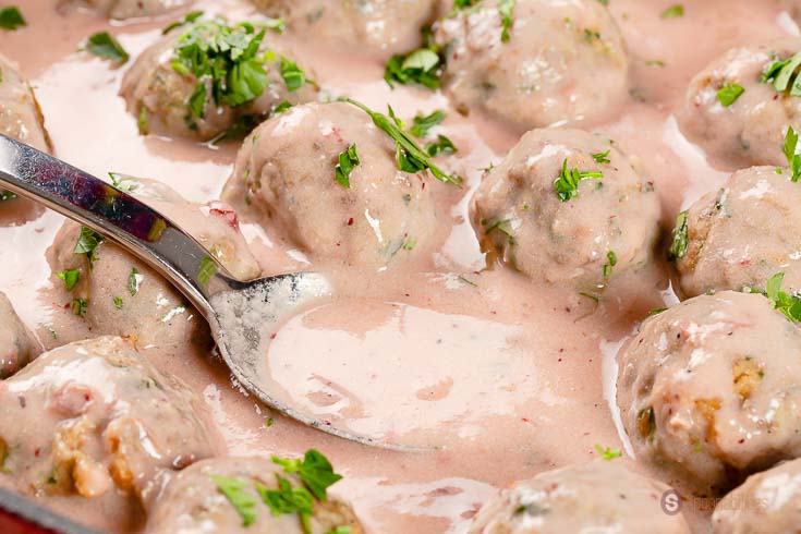 close up of lingonberry sauce on a spoon to cover Swedish meatballs